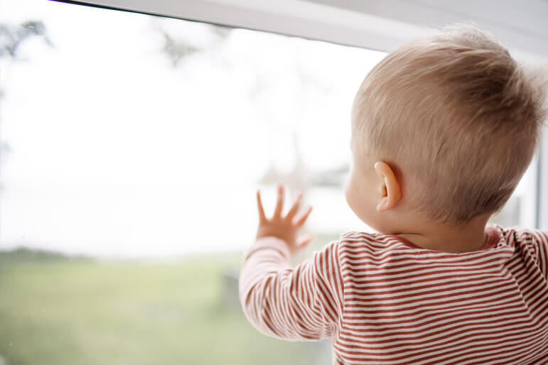 A little baby peers out of a window and its adorable.