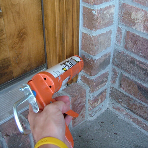 Exterior caulking being applied to the outside of the door