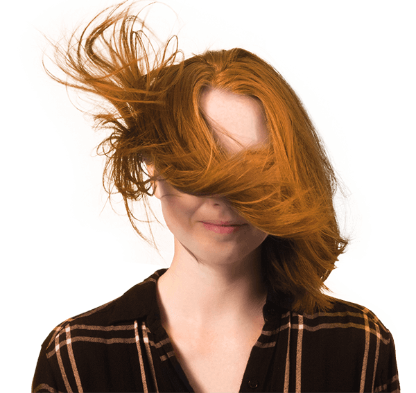 A woman wearing a plaid shirt with her hair blowing in the wind.