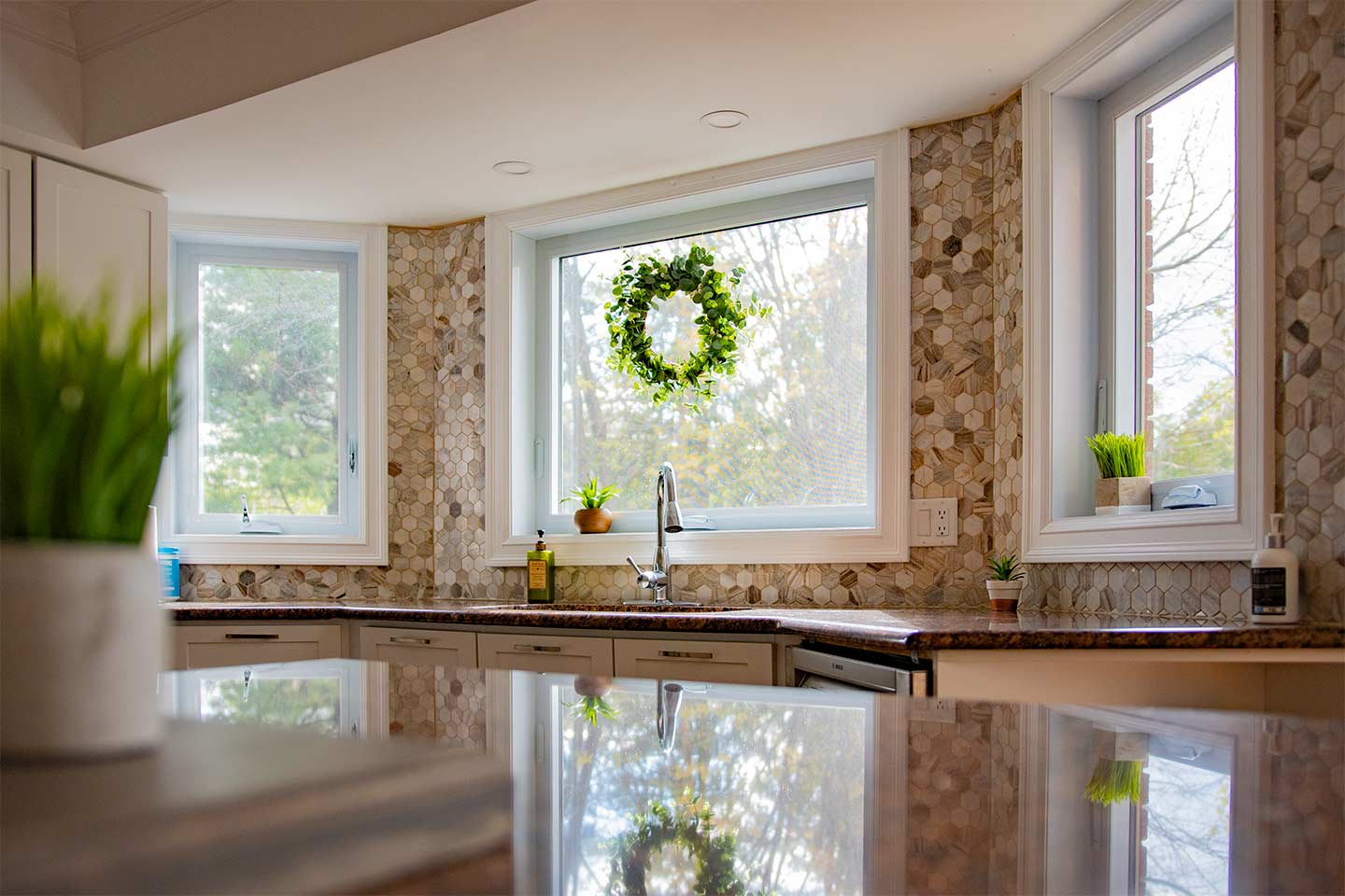 An awning window flanked by two casements in a bay configuration above a kitchen sink Frame