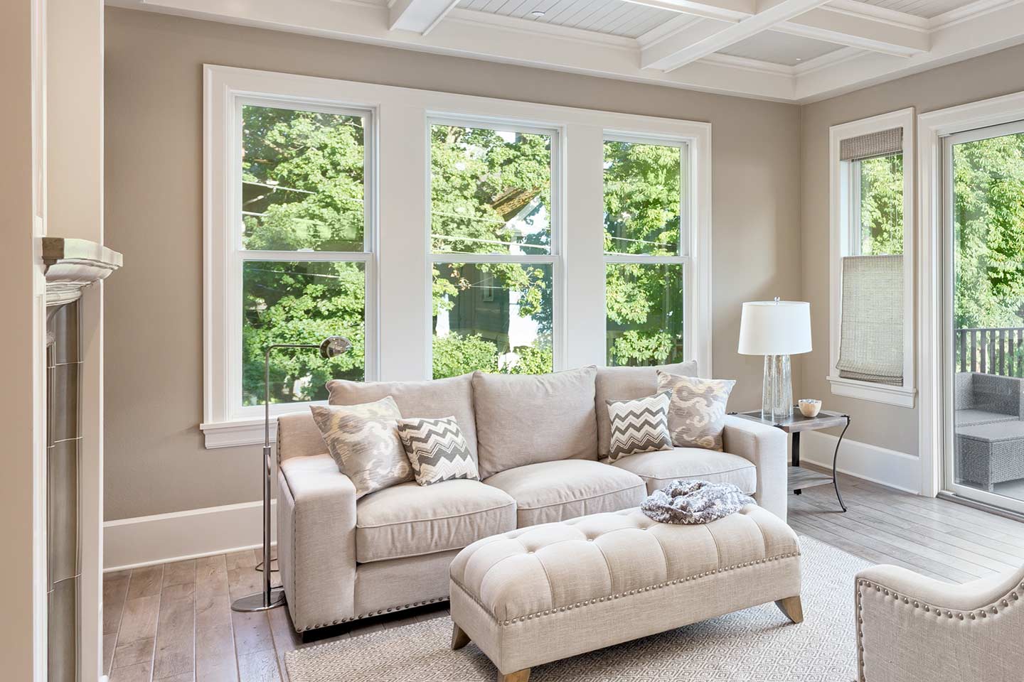 A sitting room with a couch in front of three single hung windows Frame